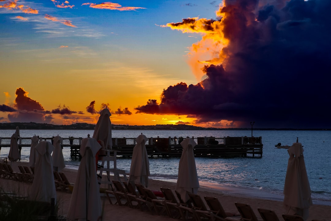 The sun is setting over the beach with umbrellas,