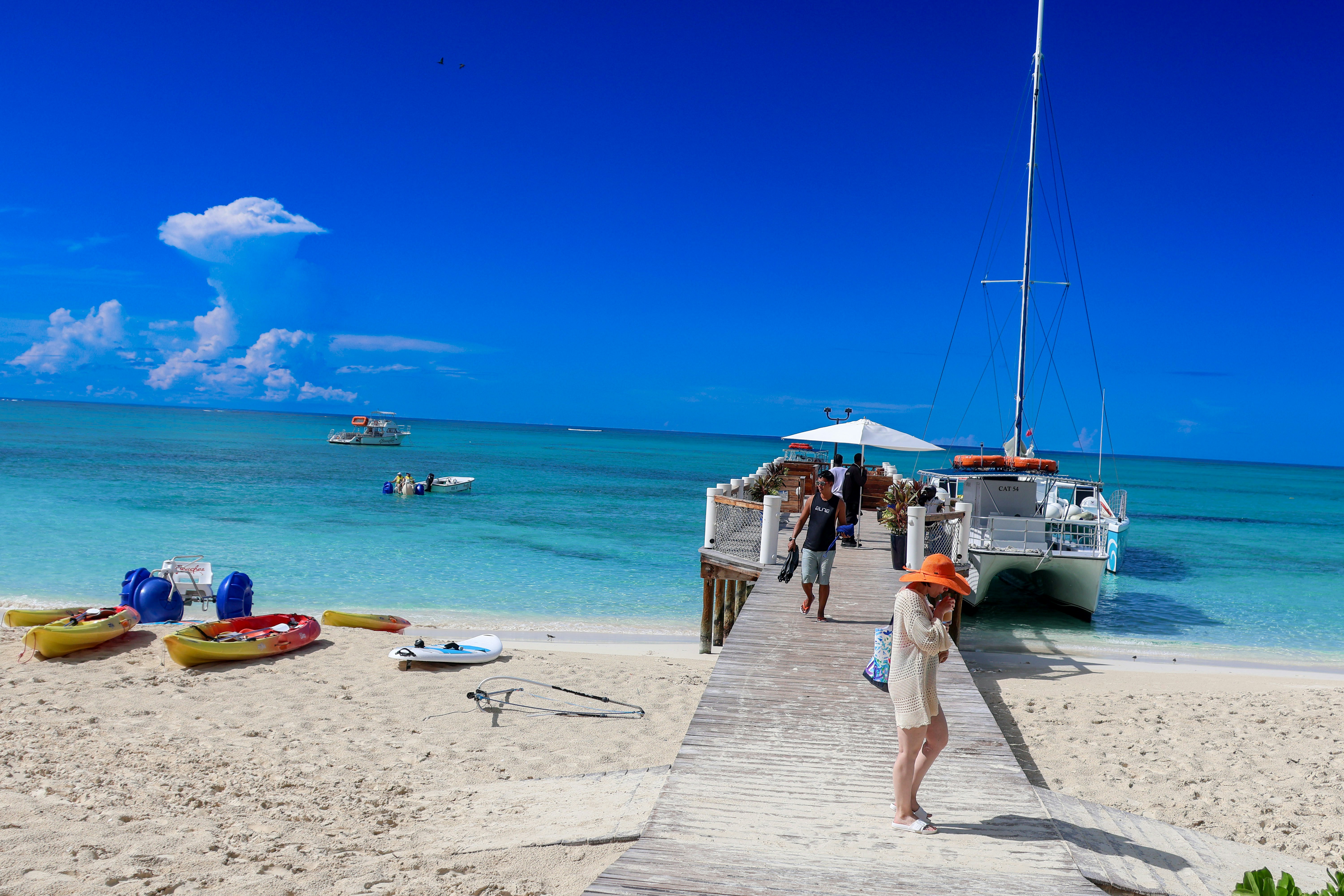 A group of people standing on a beach next to a boat