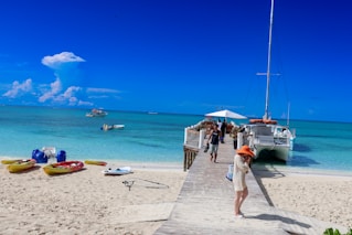 A group of people standing on a beach next to a boat