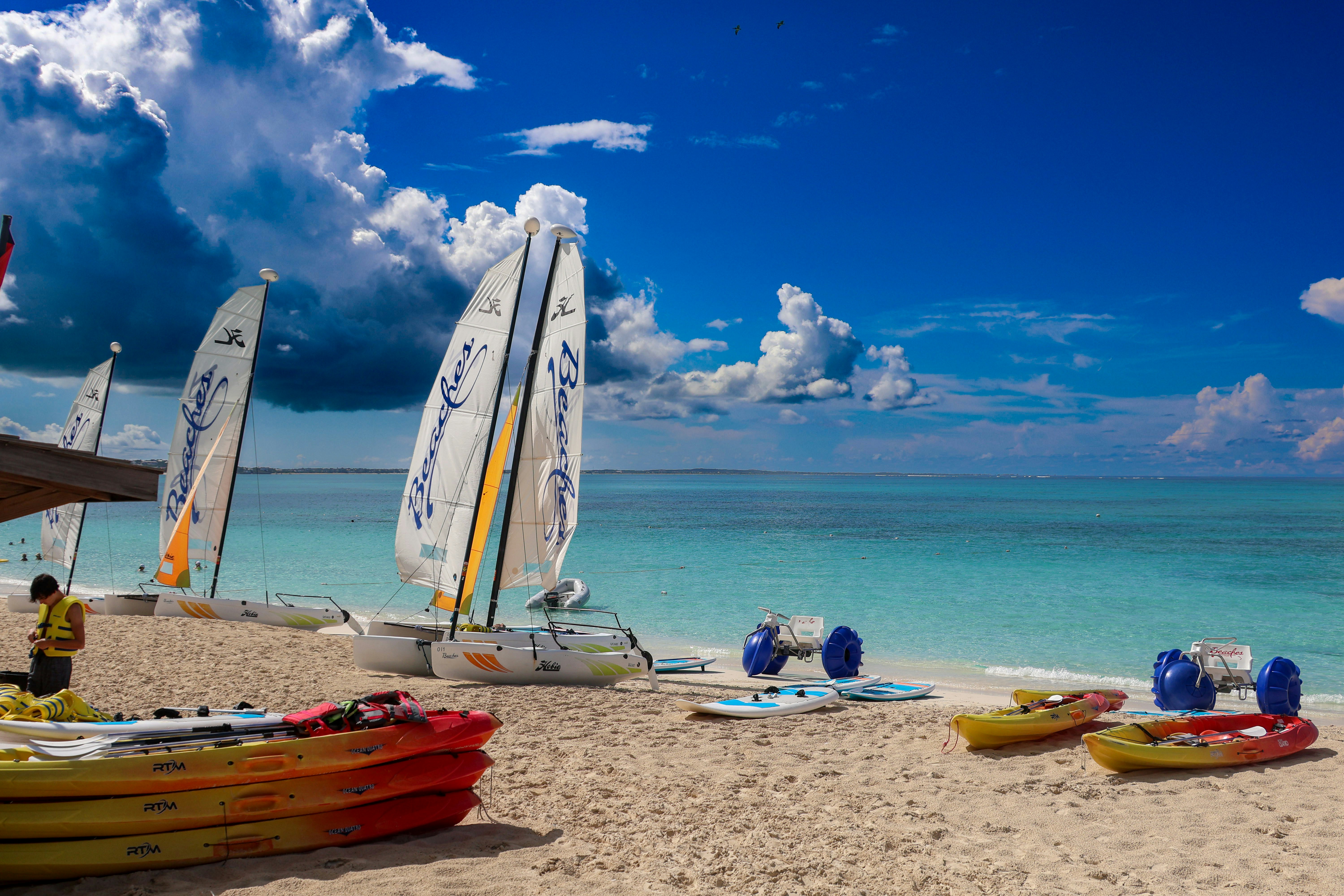Un gruppo di barche a vela sedute in cima a una spiaggia sabbiosa