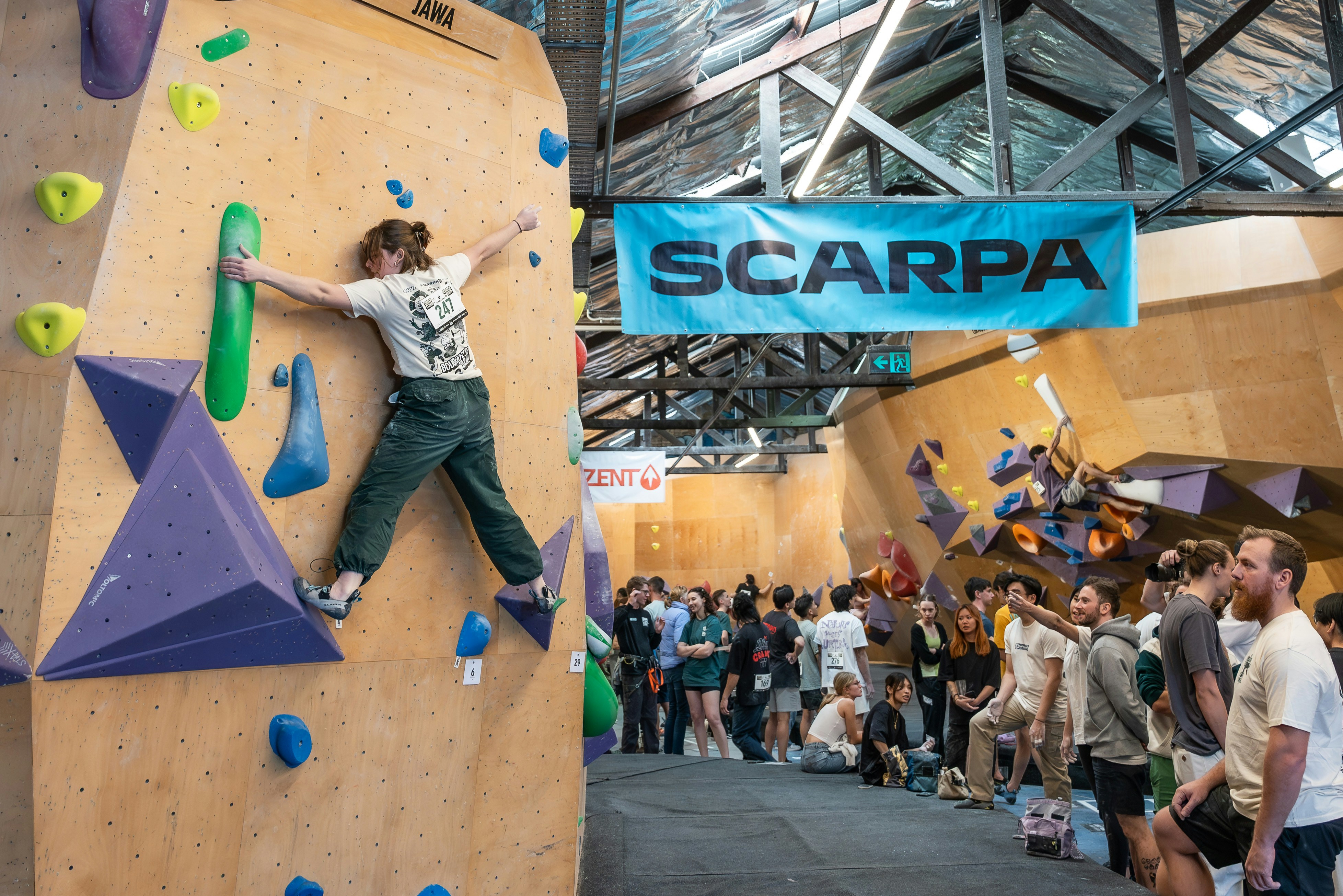 A group of people standing around a climbing wall