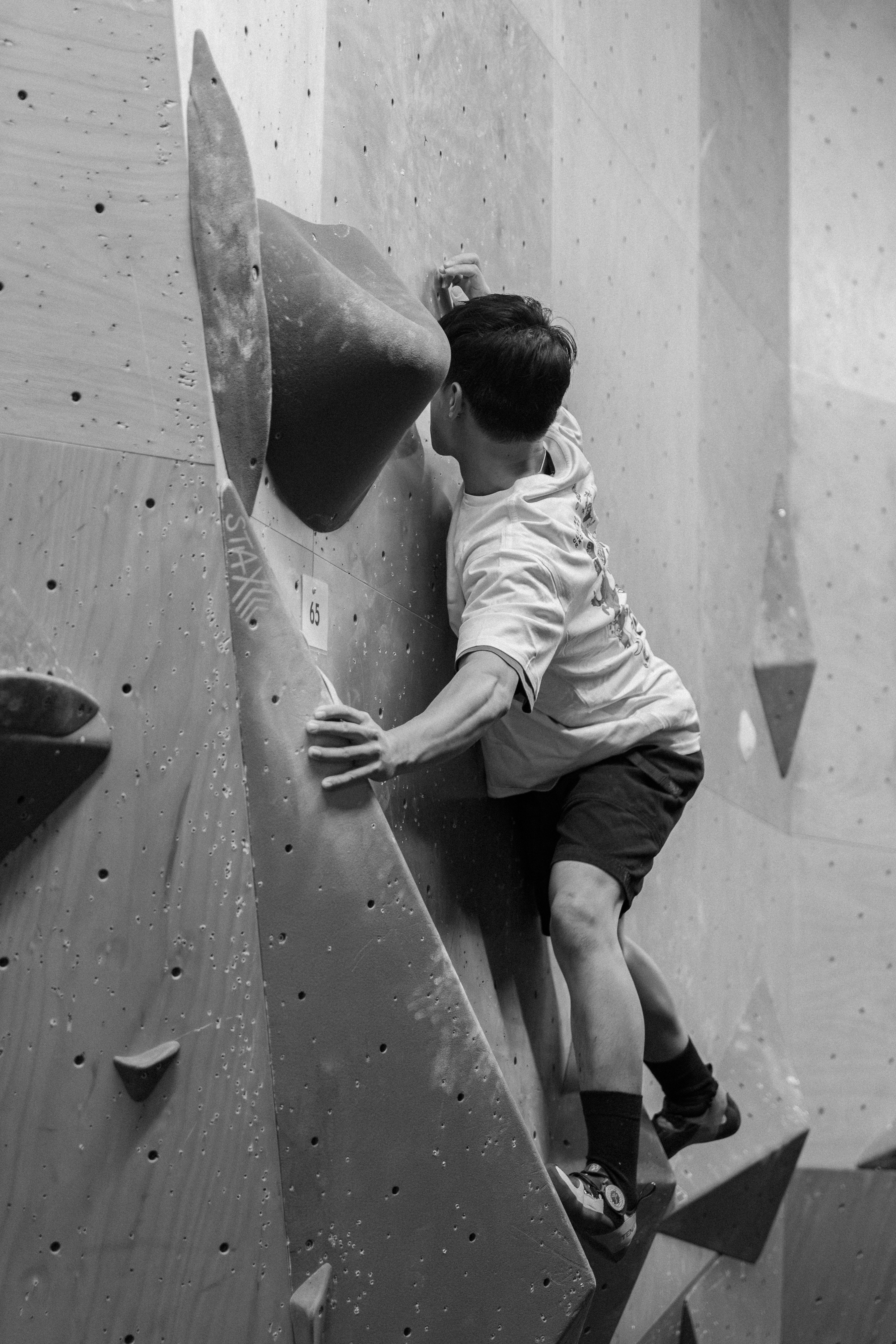 A man climbing up the side of a climbing wall