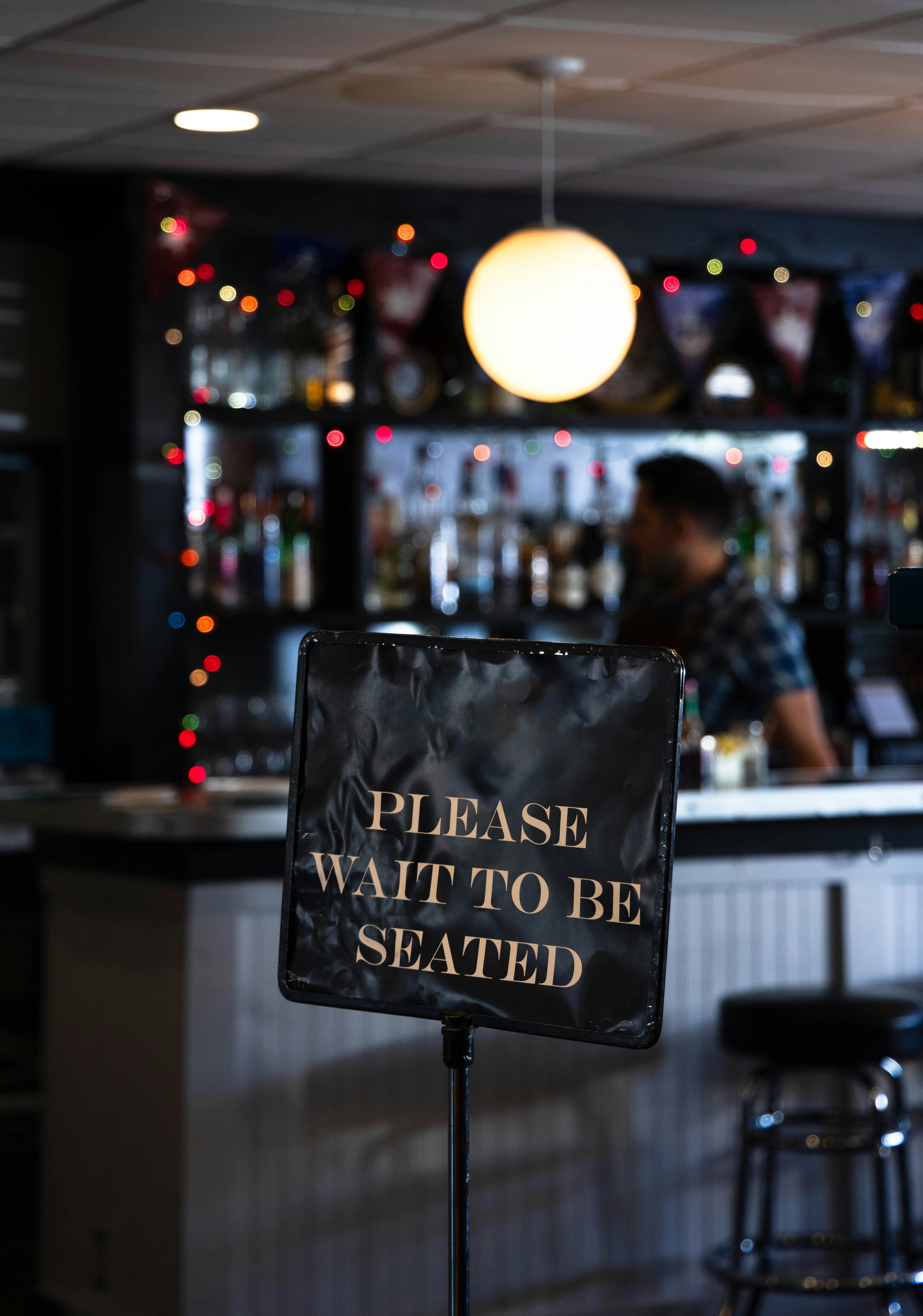 Ein Schild mit der Aufschrift "Bitte warten Sie, bis Sie vor einer Bar sitzen"