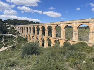 A large stone bridge over a lush green hillside