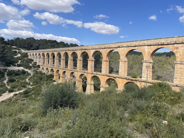 A large stone bridge over a lush green hillside