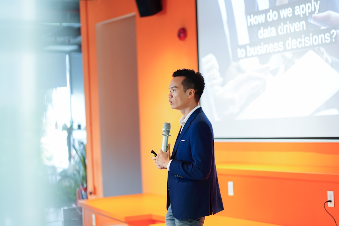 A man standing in front of a projector screen, A speaker talking about data driven organization