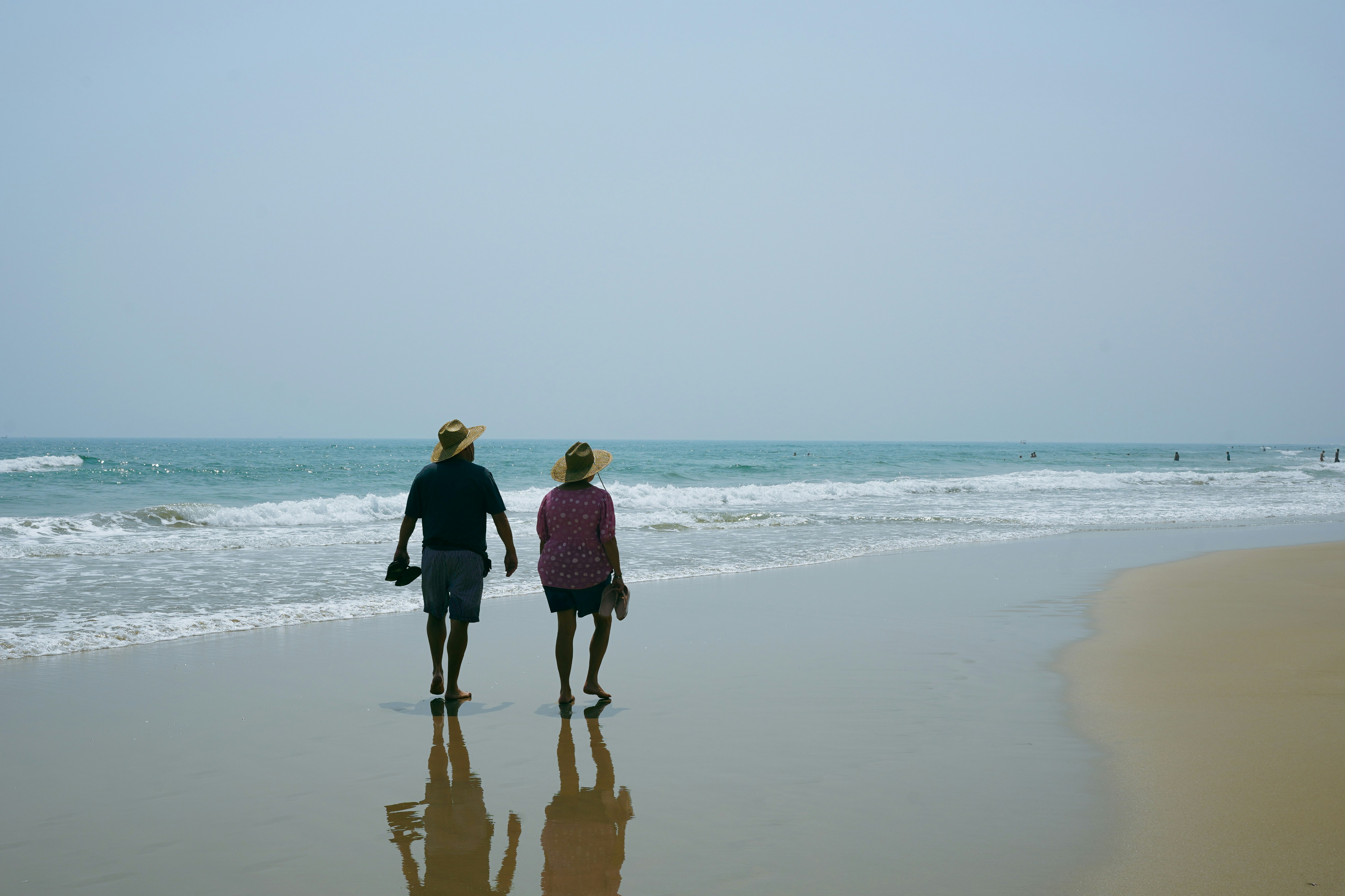 A man and a woman walking on the beach