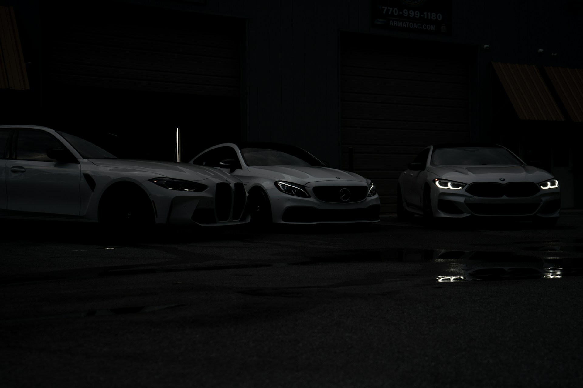 Three cars parked in a parking lot at night