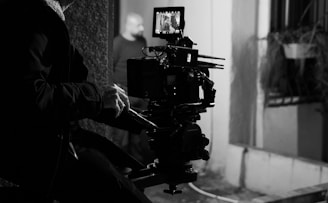 A black and white photo of a man sitting in front of a camera