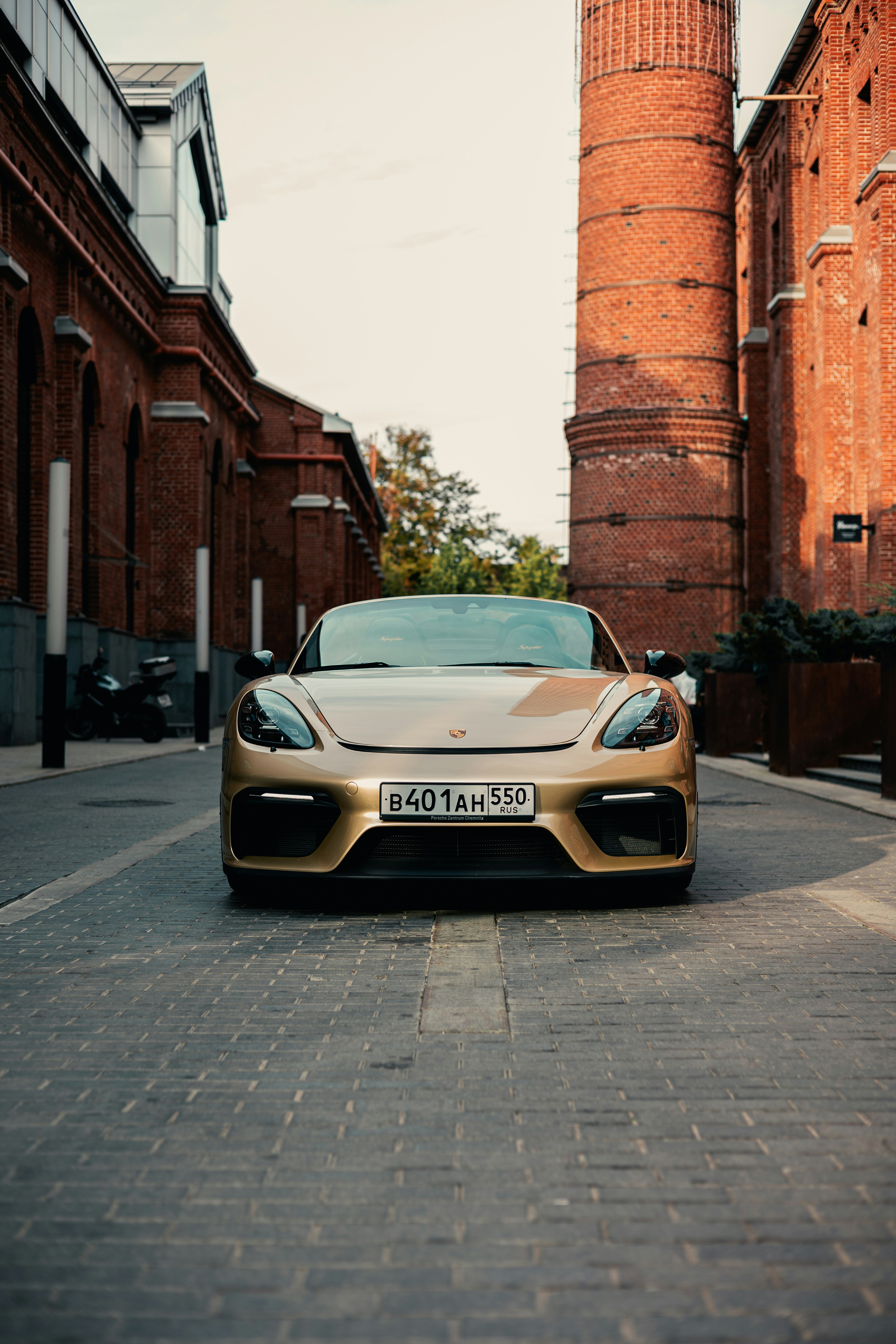 Une voiture de sport dorée garée devant un bâtiment en brique