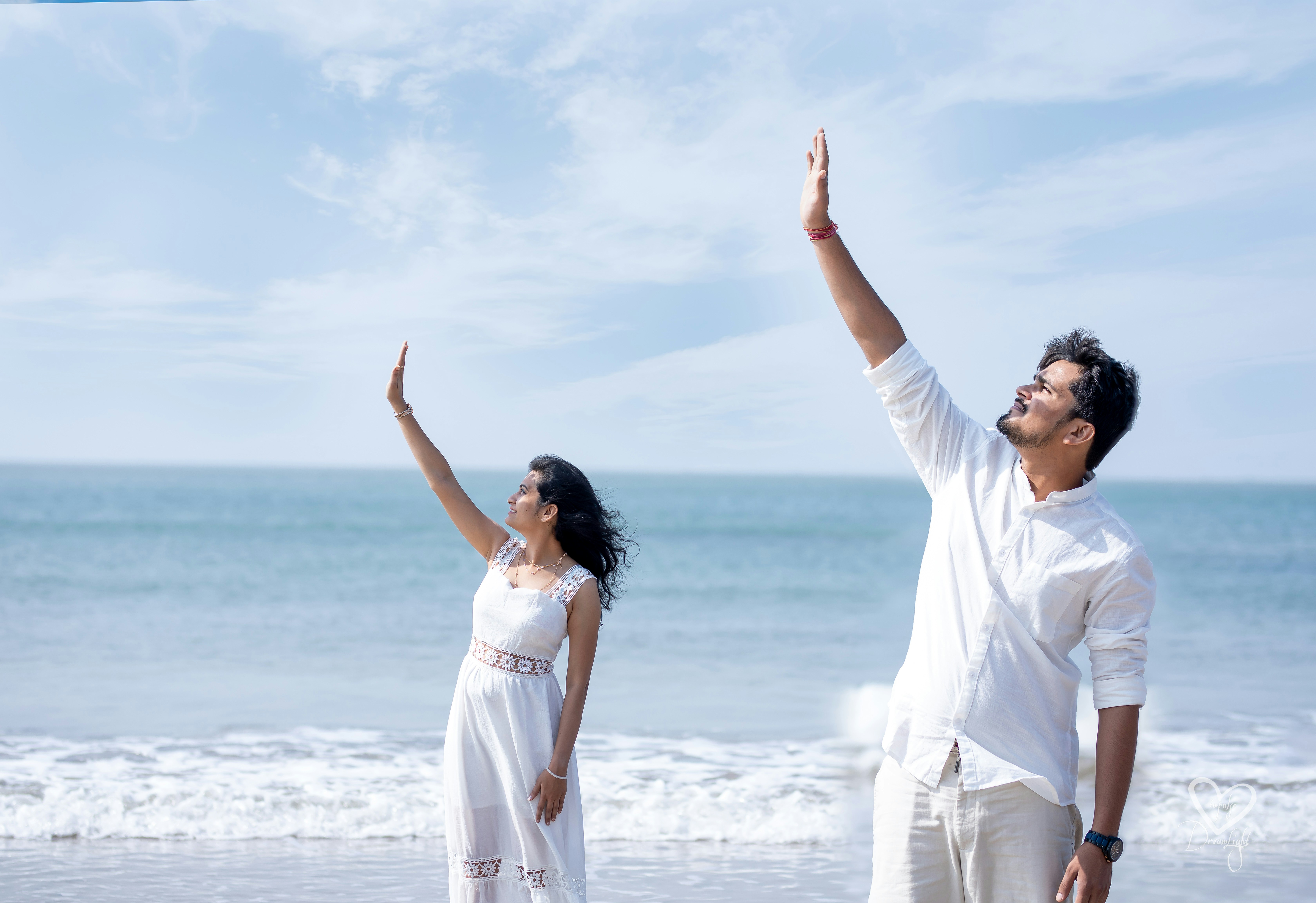 A man and woman standing on a beach next to the ocean