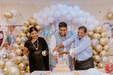 A group of people standing around a table with a cake