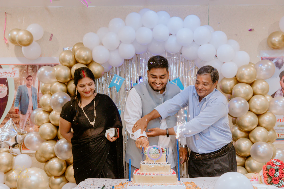 Couple cutting a cake at an anniversary party with gold balloons
