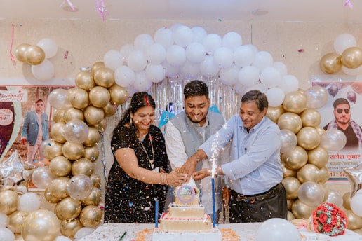 A group of people standing around a table with a cake