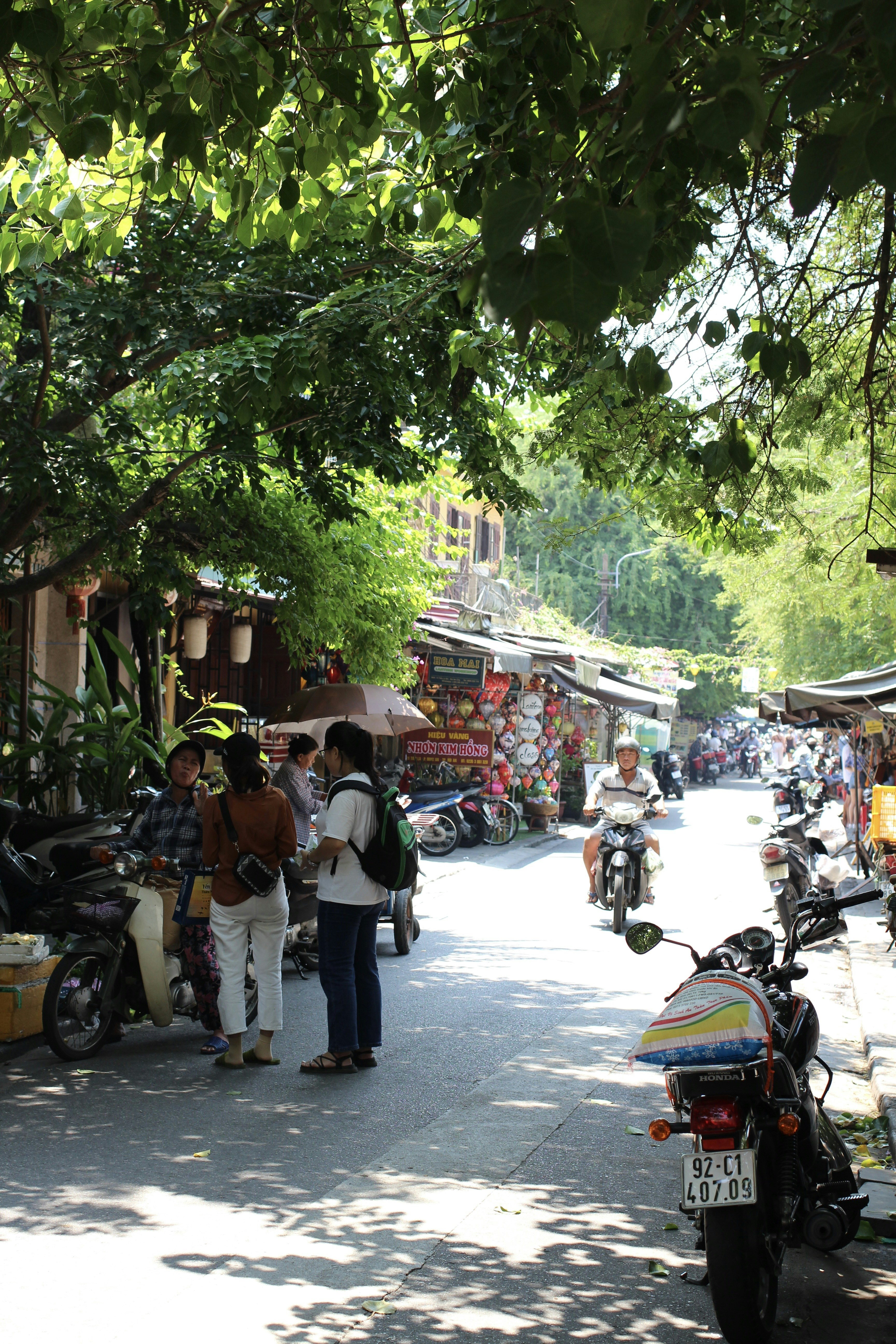 A group of people walking down a street next to parked motorcycles