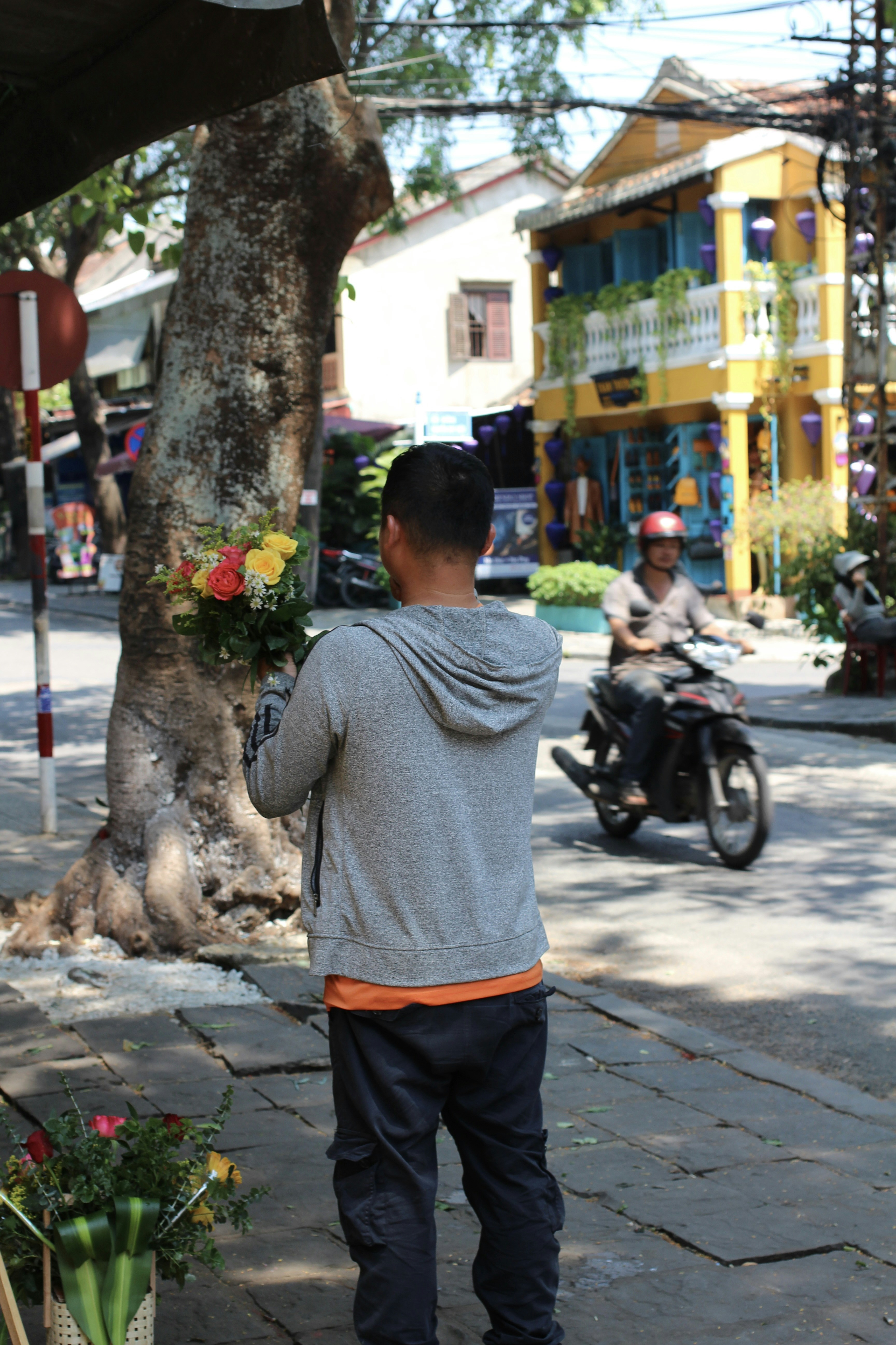 A man standing on a sidewalk next to a tree
