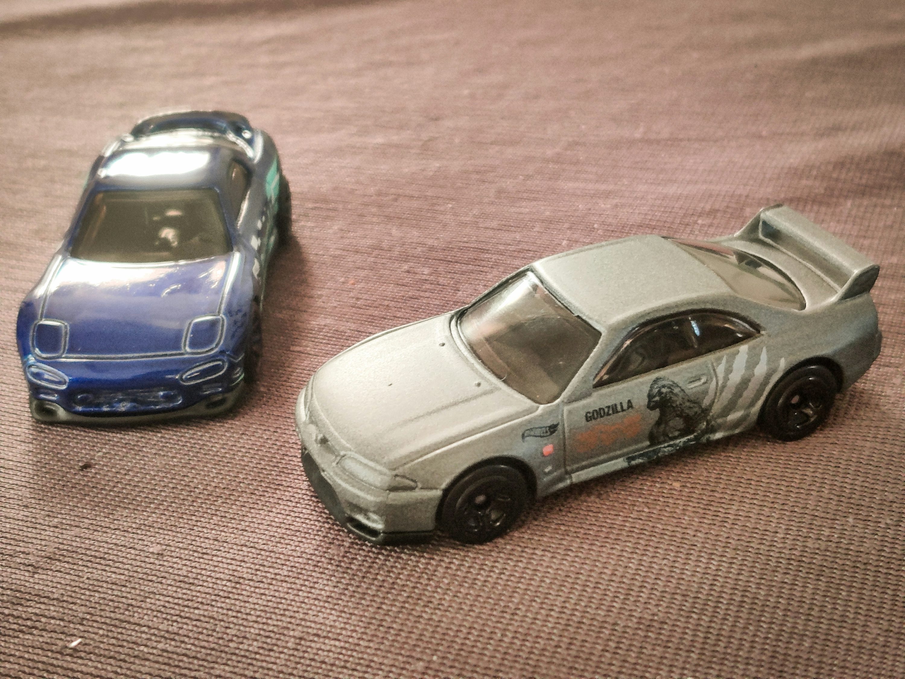 Two toy cars sitting on top of a bed
