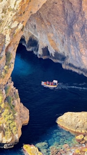 A boat in a body of water near a cliff