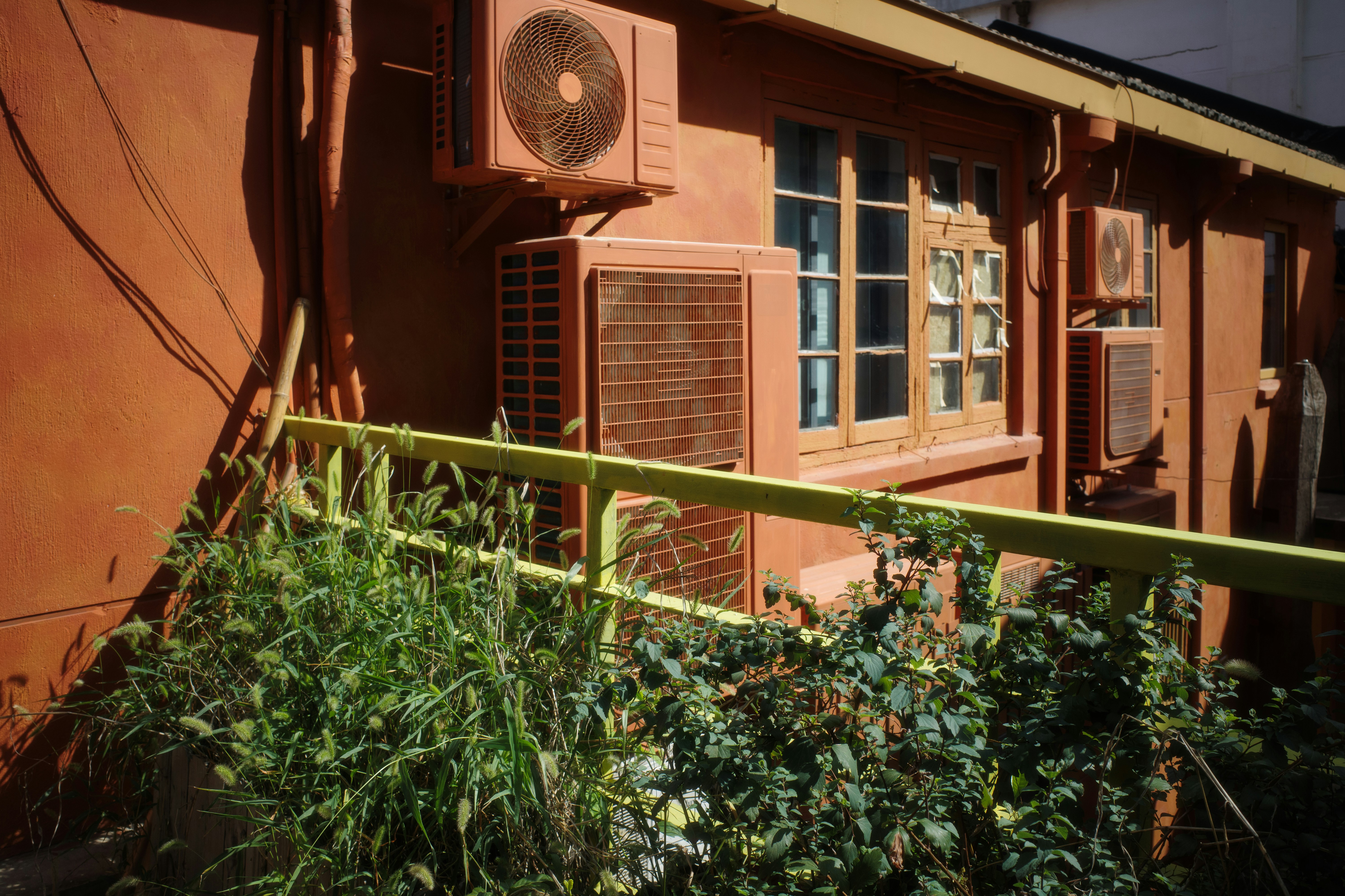 A red building with a window and a green fence