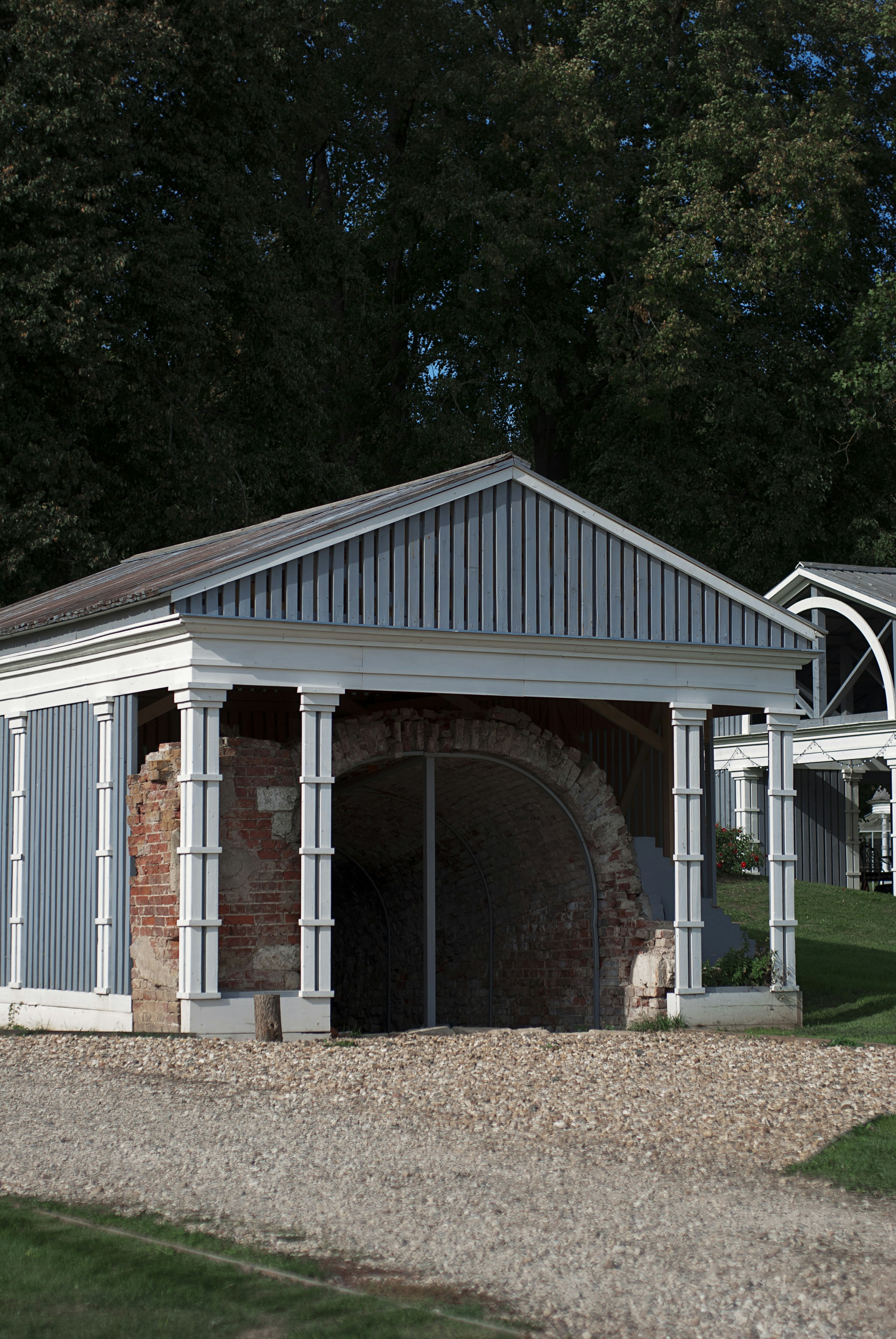 A brick building with a white roof next to a green field