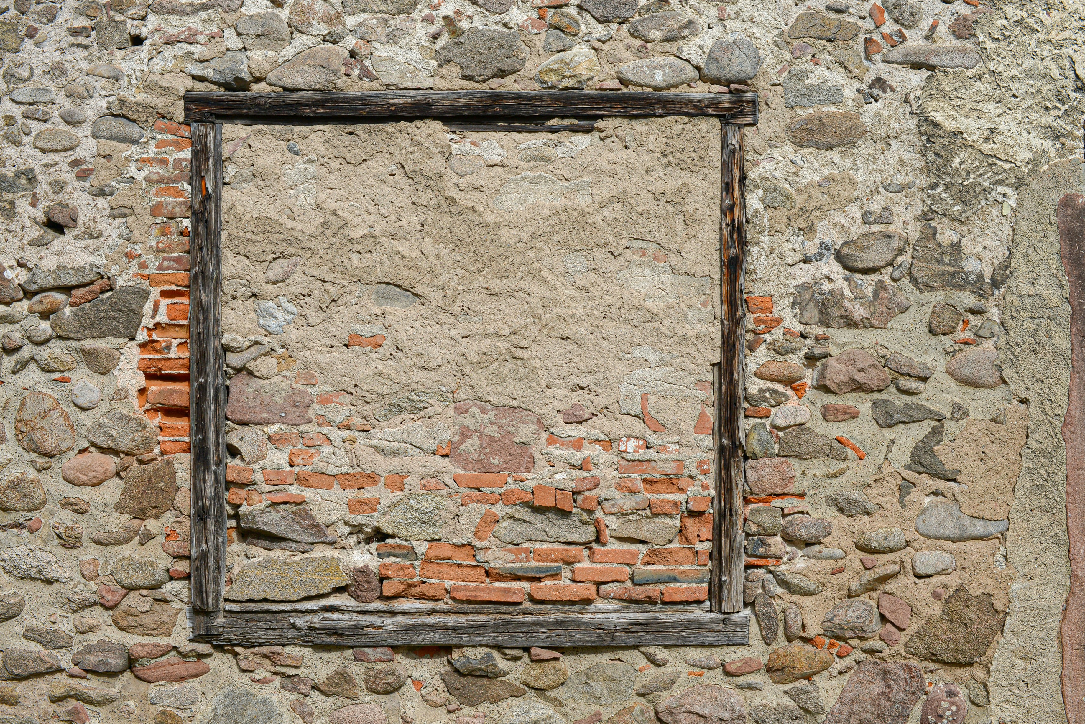 A stone wall with a window in the middle of it