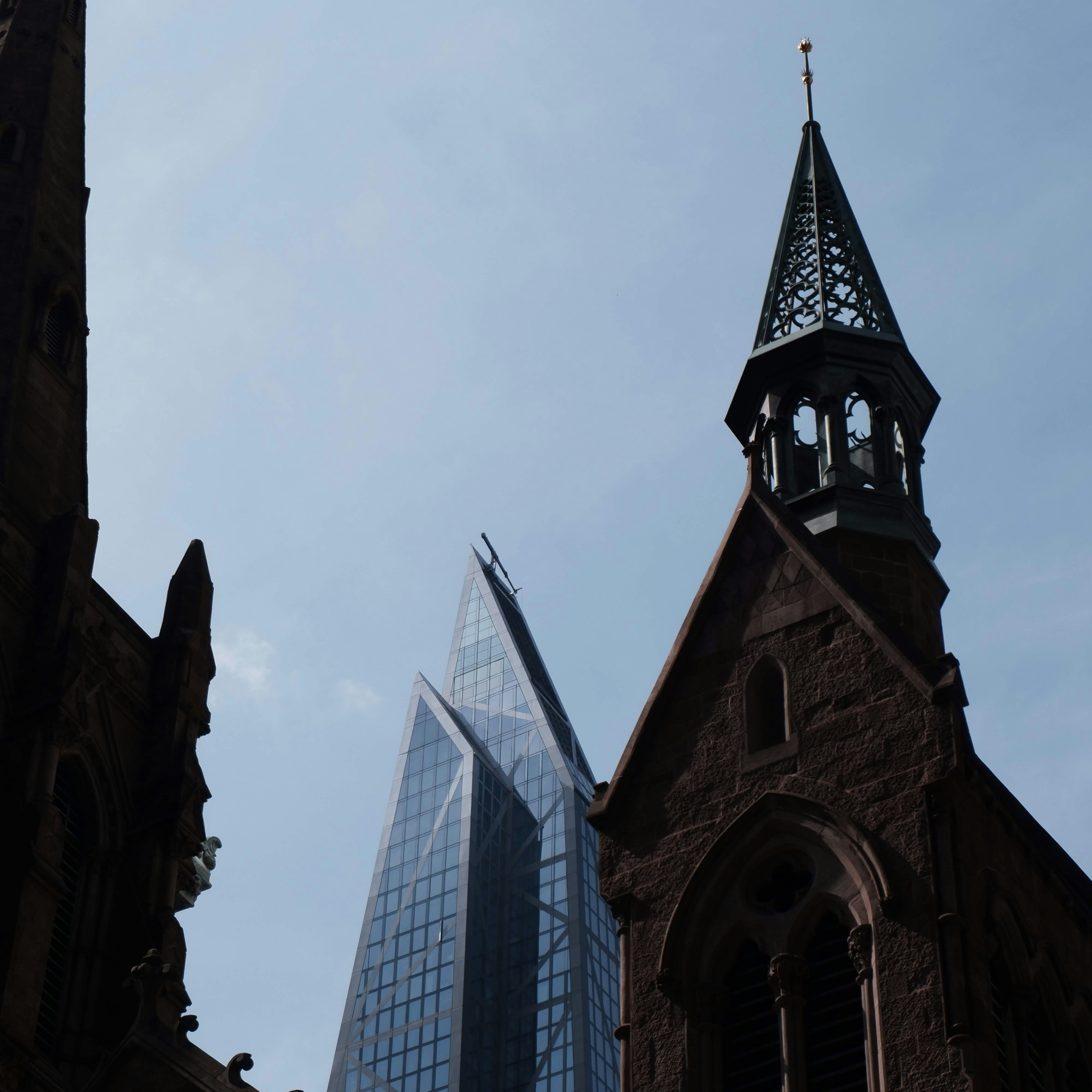 An old church with a steeple and a tall building in the background