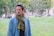 A man standing in a park with a scarf around his neck