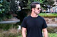 A man in a black t - shirt is holding a skateboard