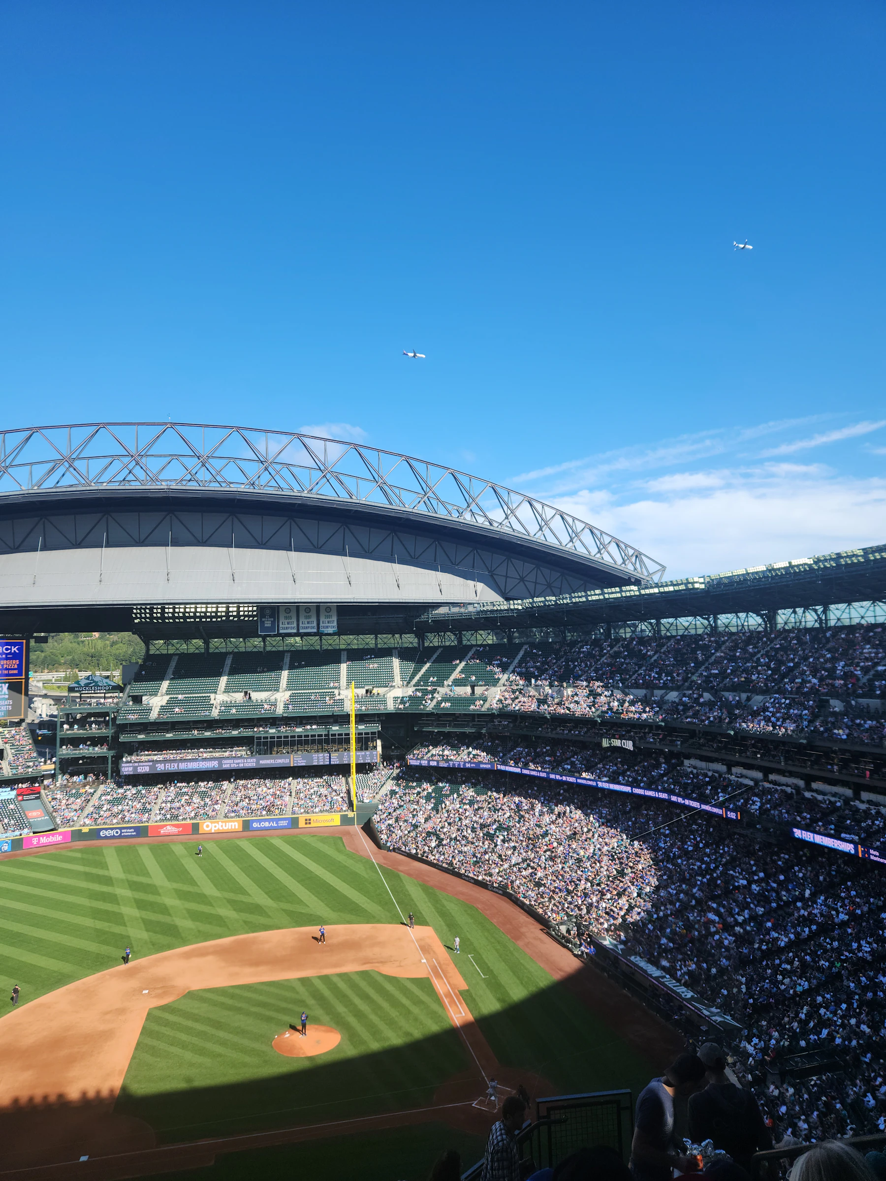 The view from the upper deck of a ballpark on a clear day, with the whole field, the roof and the stands on the far side in sight