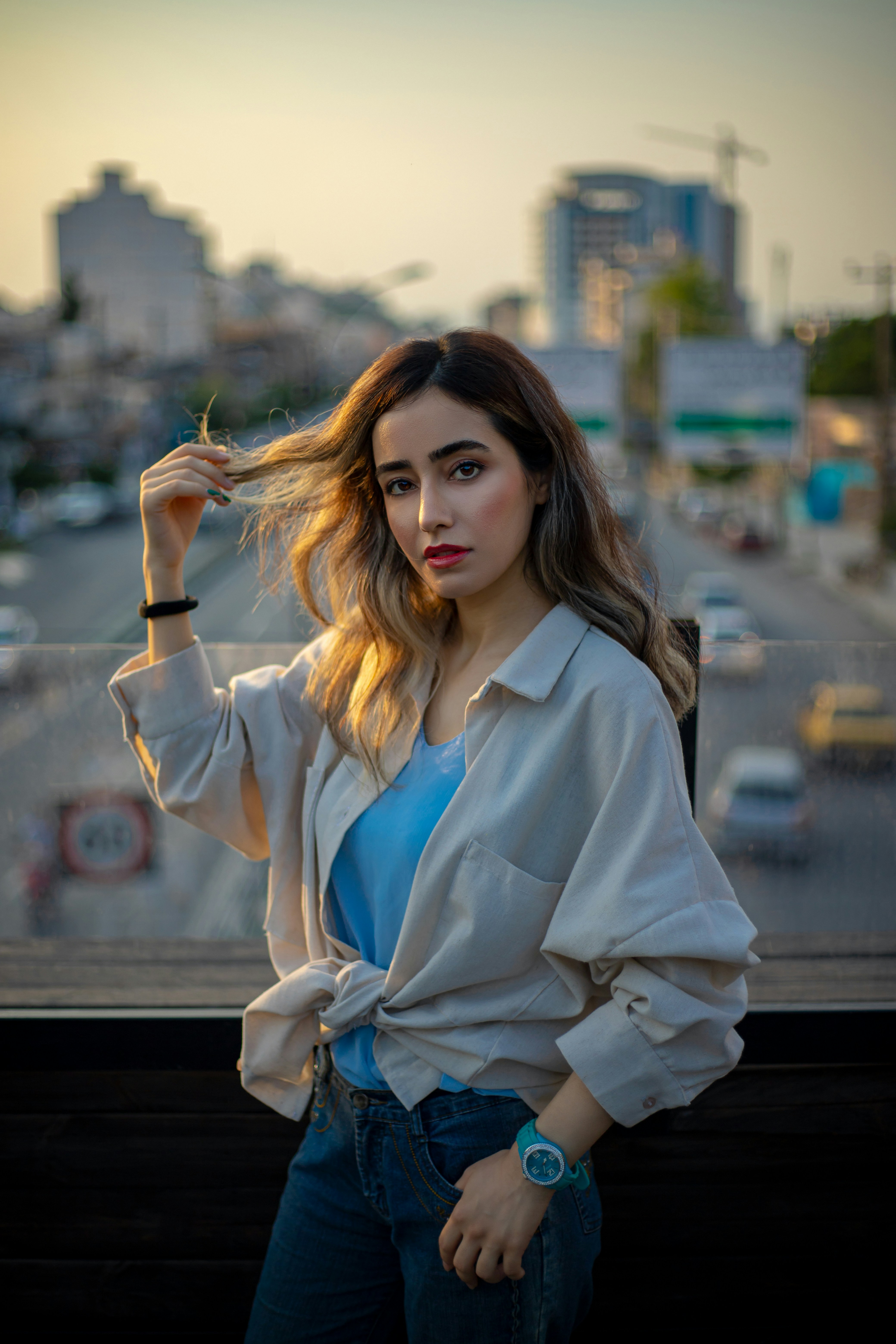 A woman standing next to a window with a city in the background
