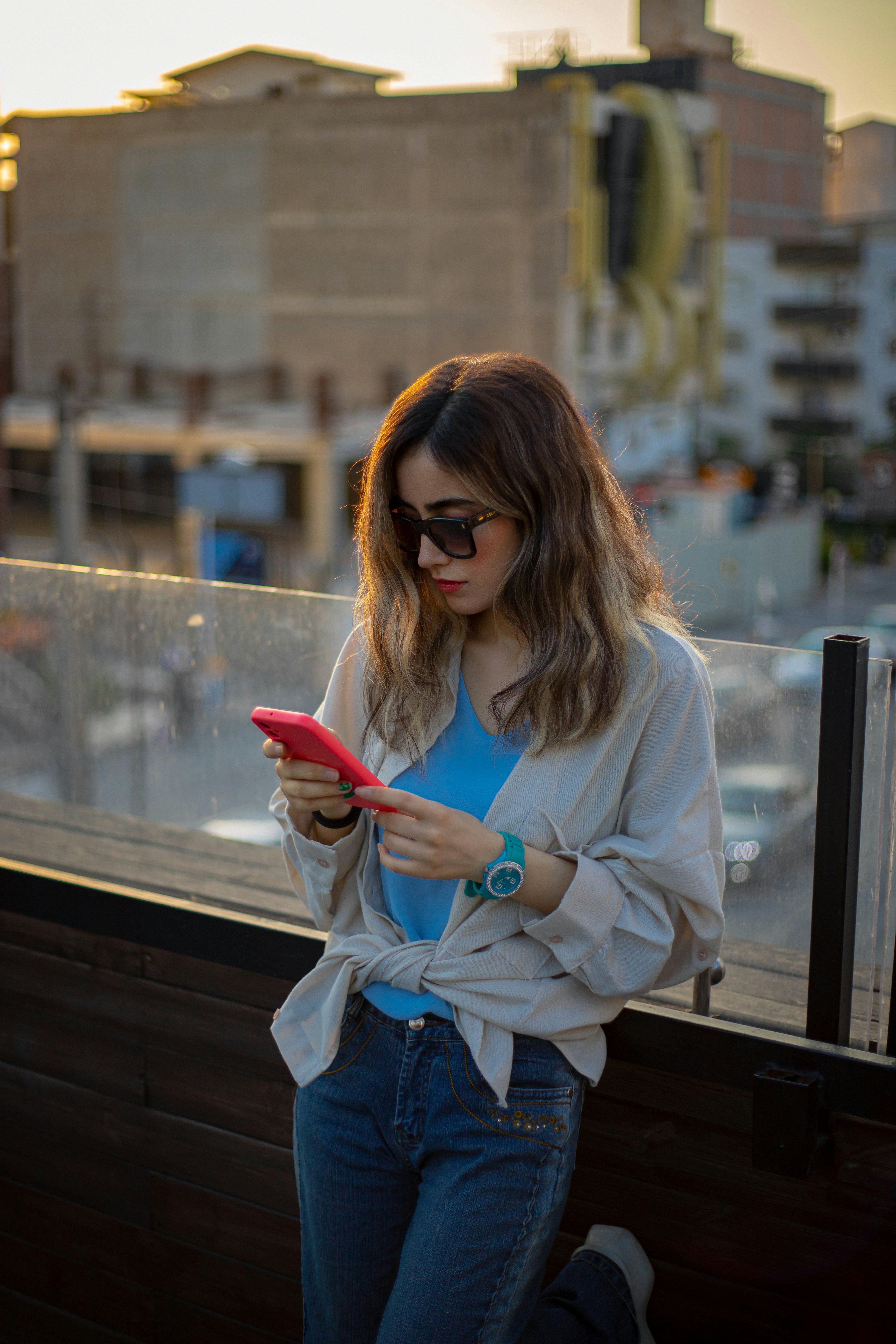 A woman standing on a balcony looking at her phone