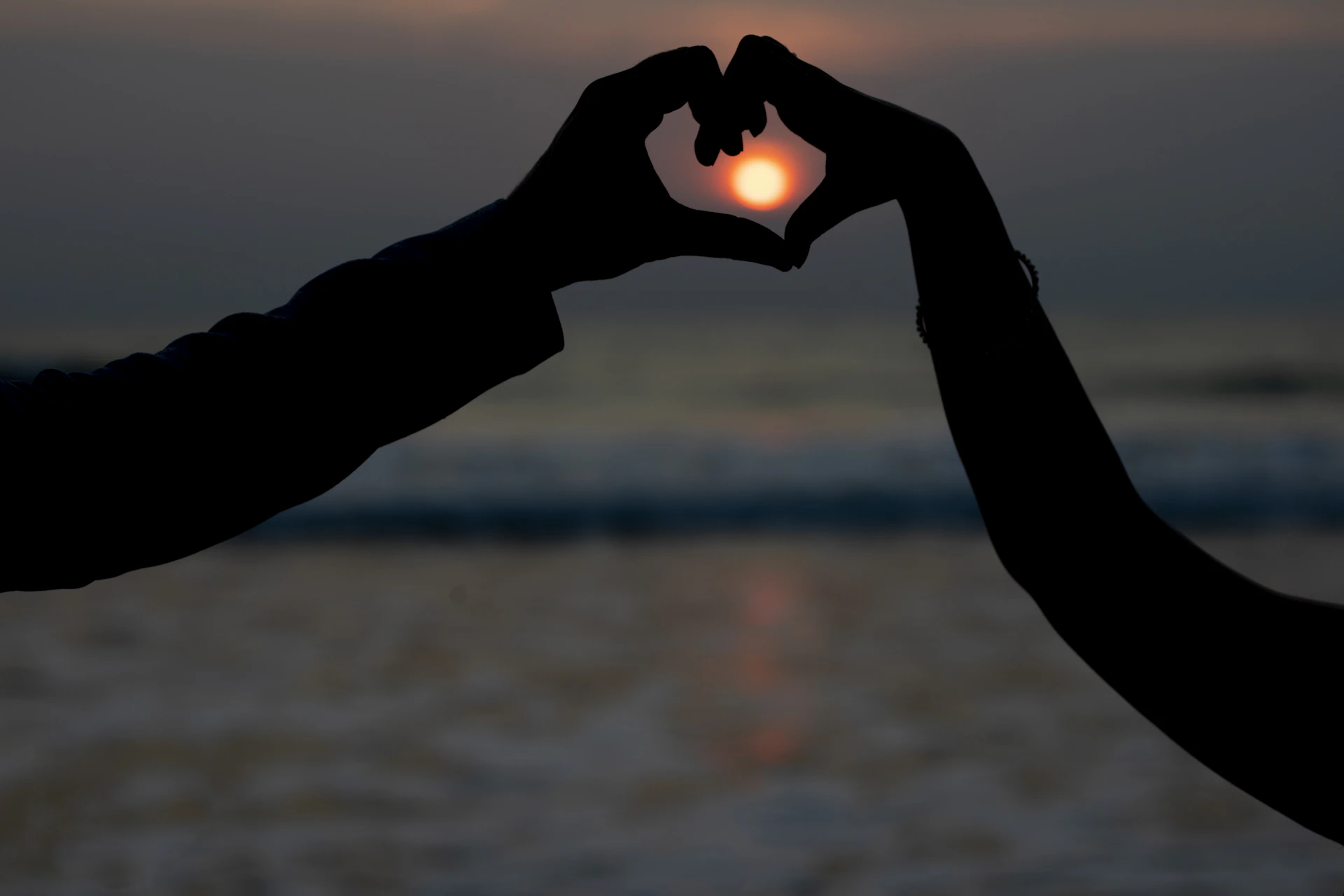 Two people making a heart shape with their hands