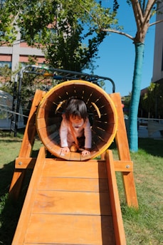 A young girl playing inside of a wooden structure