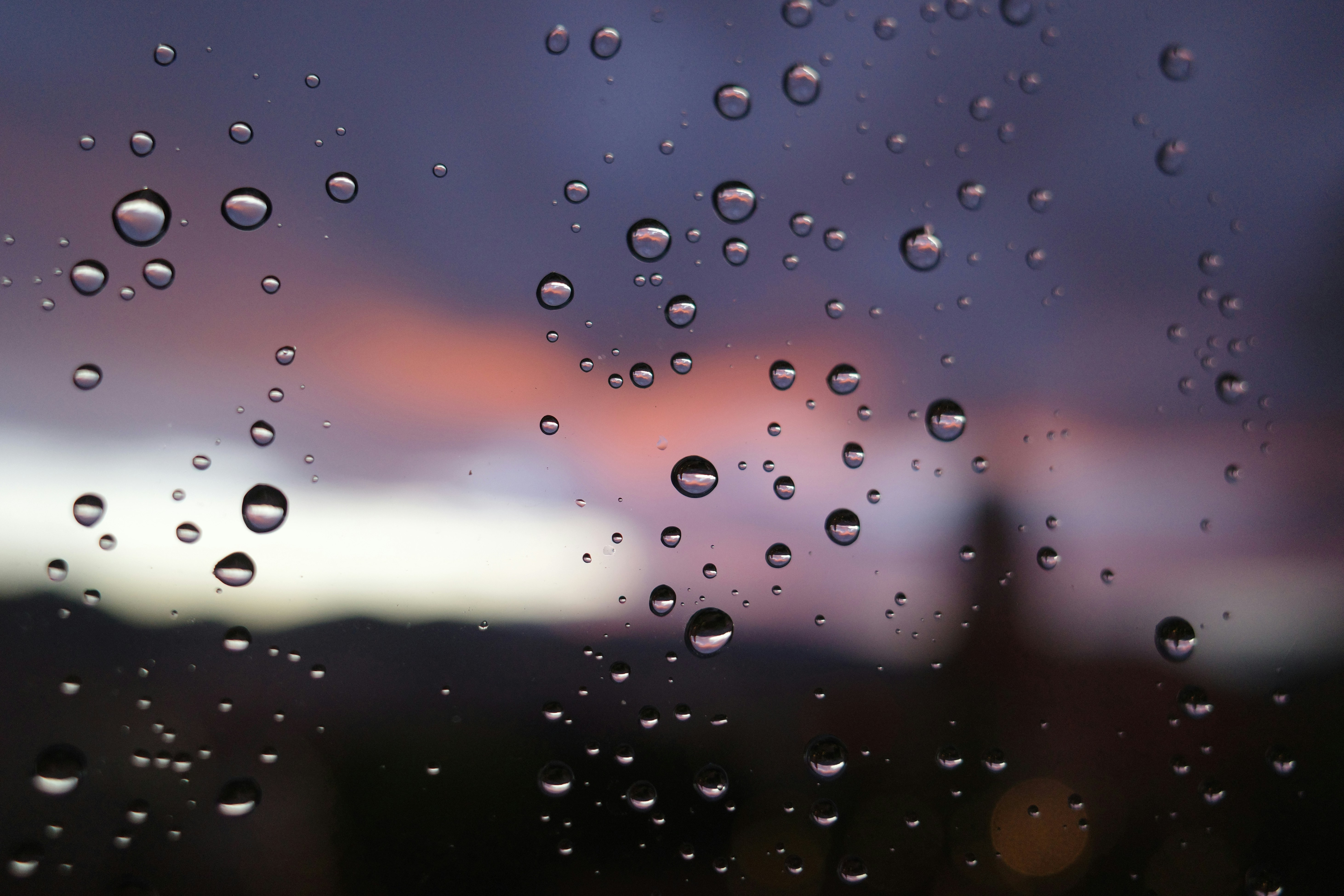 Rain drops on a window with a sunset in the background