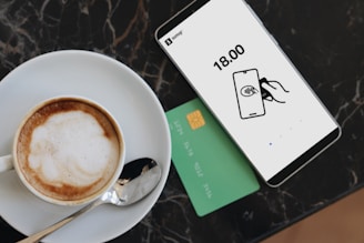 A cup of coffee on a saucer next to a credit card