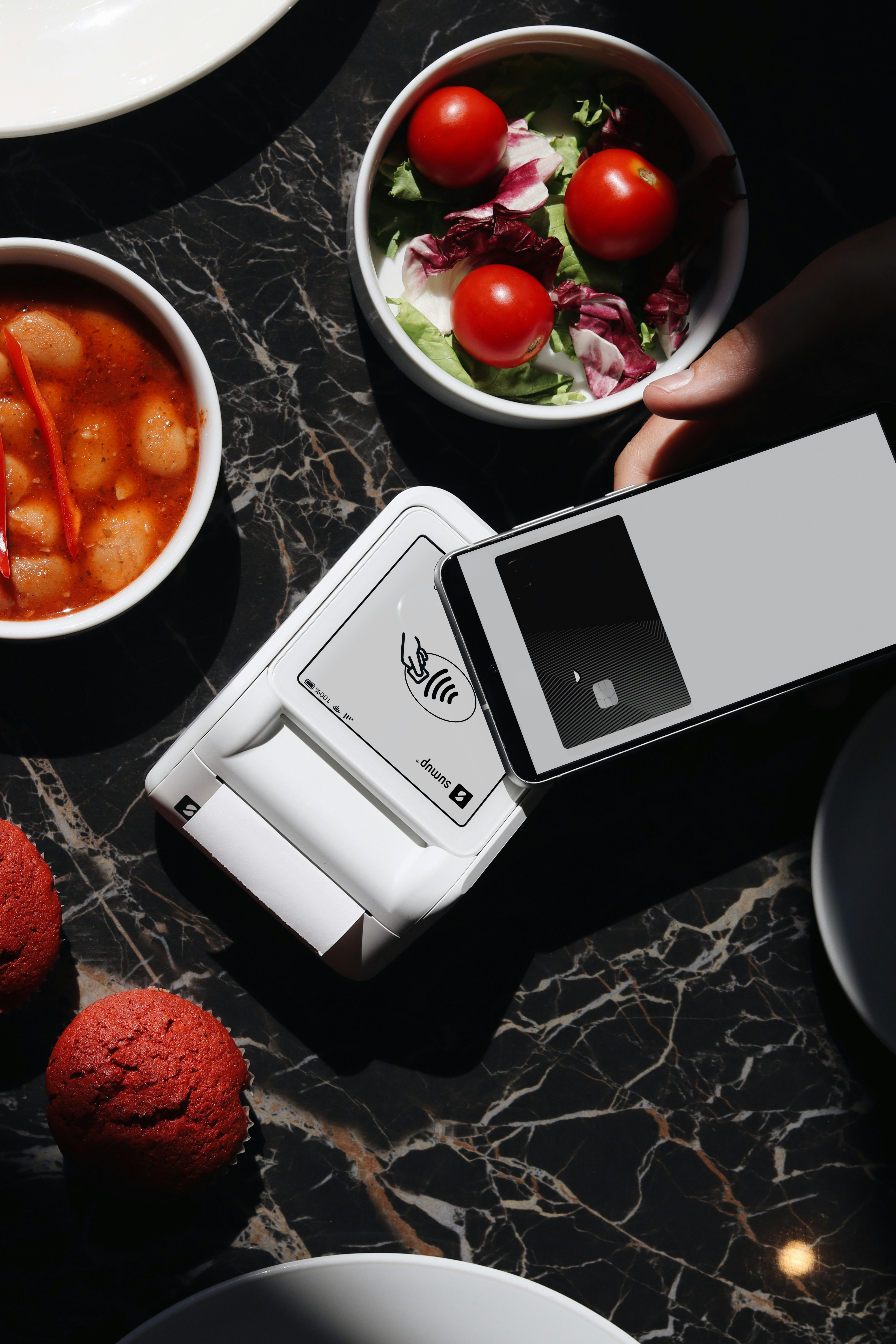 A person holding a smart phone over a table of food
