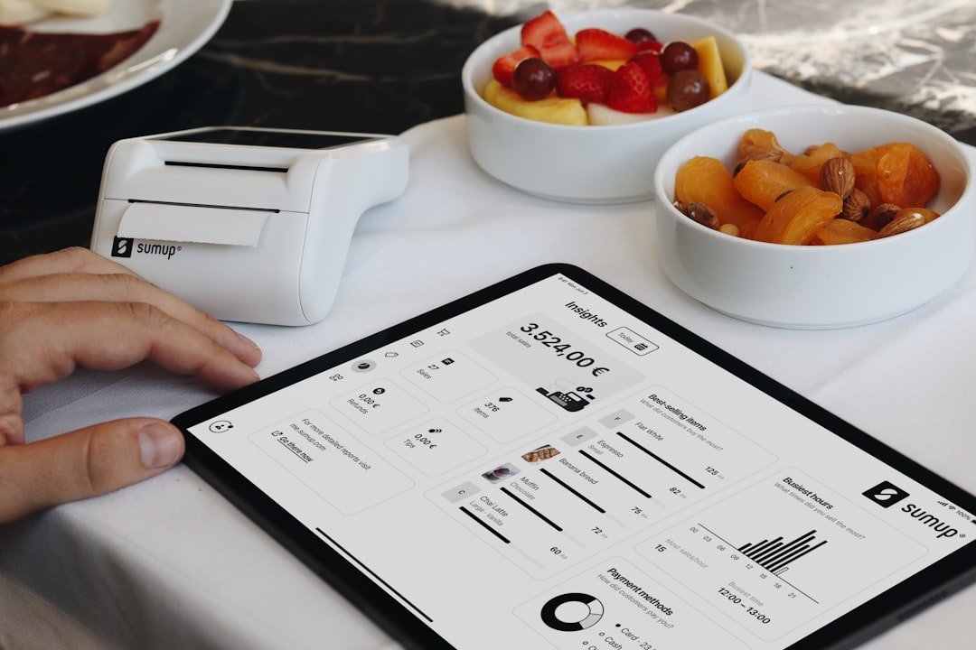 A person sitting at a table with a tablet, A free POS system integrated with a tablet, providing small businesses with real-time insights and efficient management tools. With easy access to sales data, inventory tracking, and customer analytics, this system is perfect for restaurants, cafes, and retail shops. The portable receipt printer and intuitive interface make managing transactions seamless, offering a complete, tech-driven solution for business owners looking to streamline their operations and grow their businesses. Ideal for those seeking a free, mobile register and business management system to drive success.
