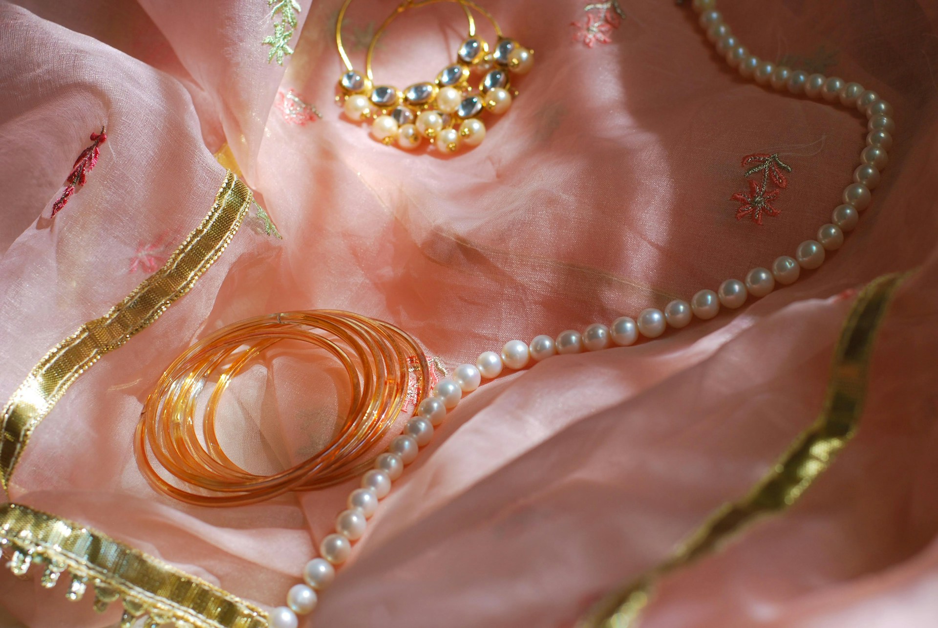 A close up of jewelry on a pink cloth