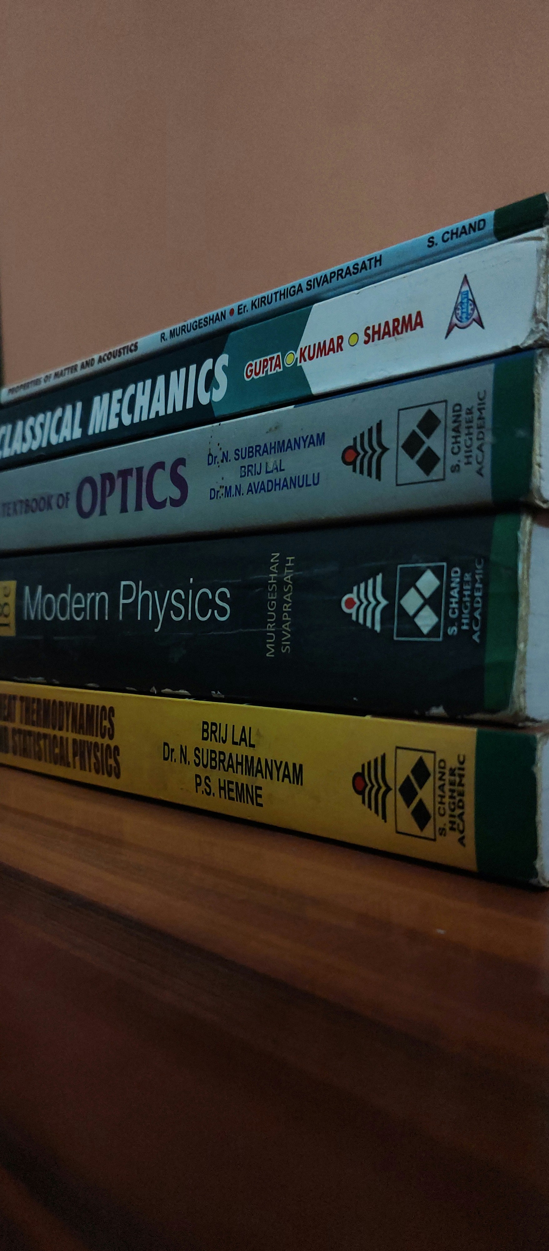 Stack of physics problem books, worn covers, well-used study materials