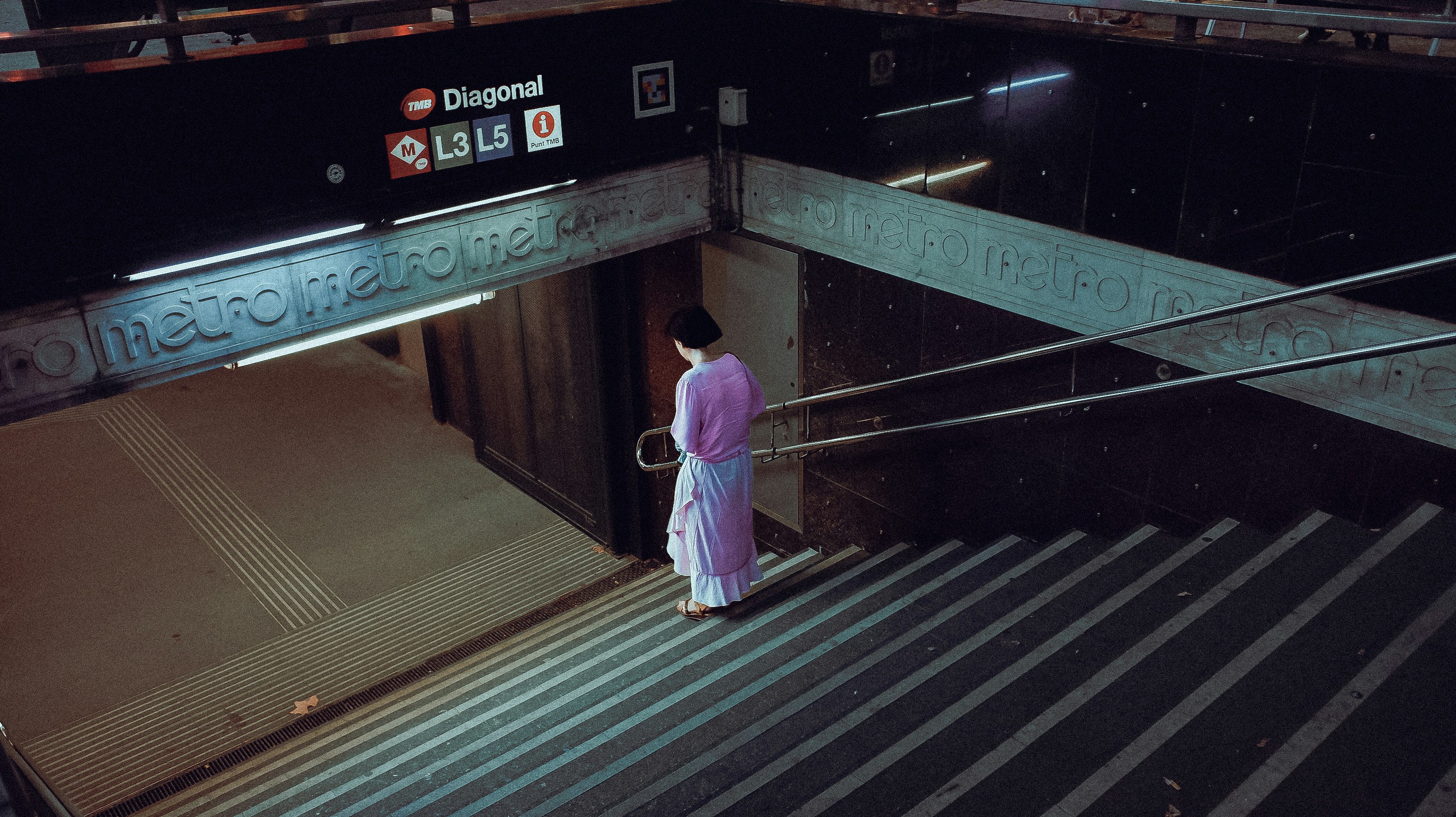 A woman in a pink dress standing on a staircase