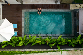 A person sitting in a swimming pool with an umbrella