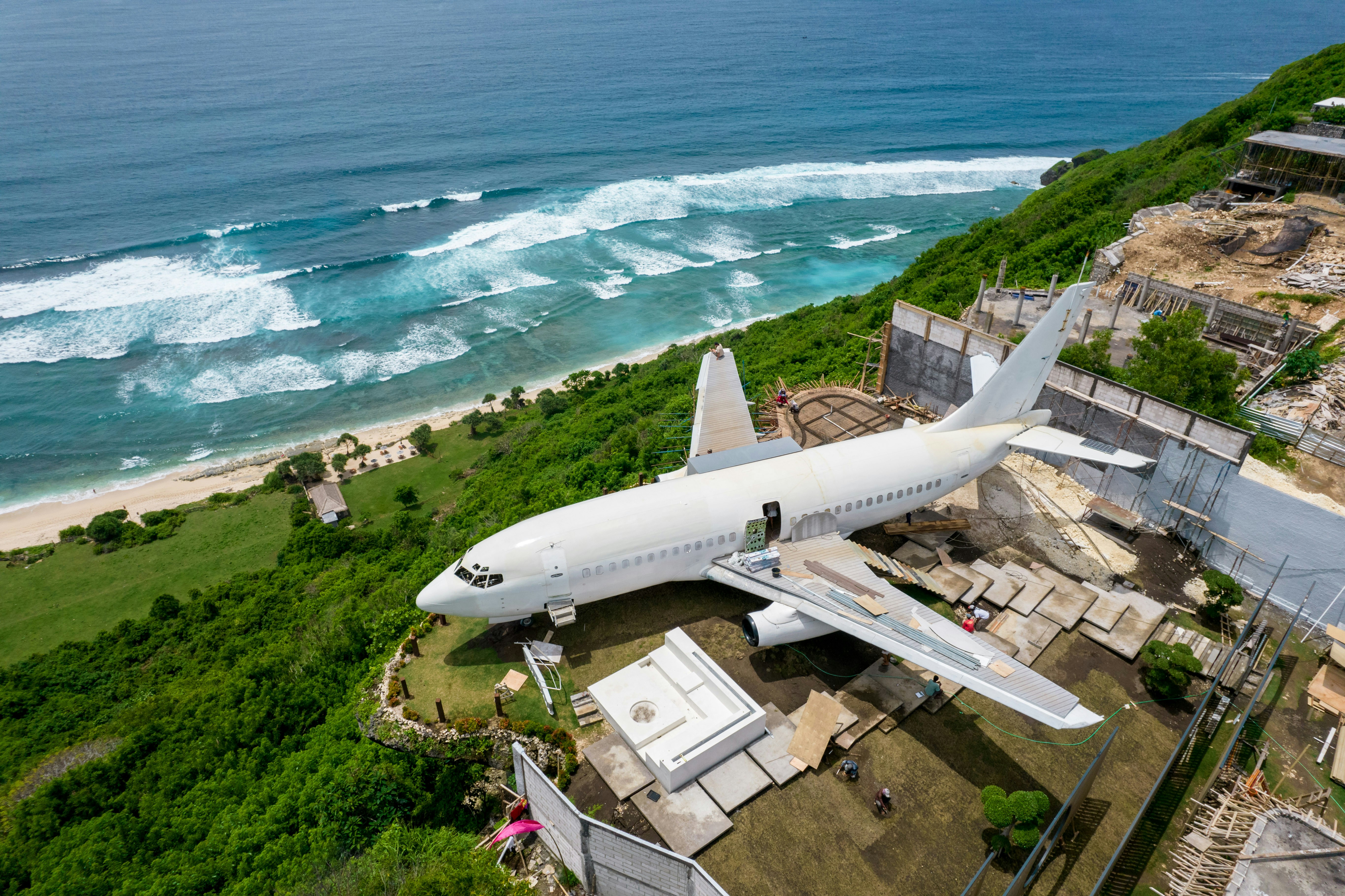 An airplane flying over a lush green hillside next to the ocean