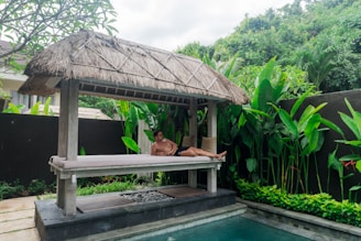 A man laying on a bench next to a pool