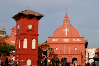 A red church with a clock tower in front of it