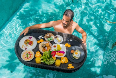A man in a pool with a tray of food
