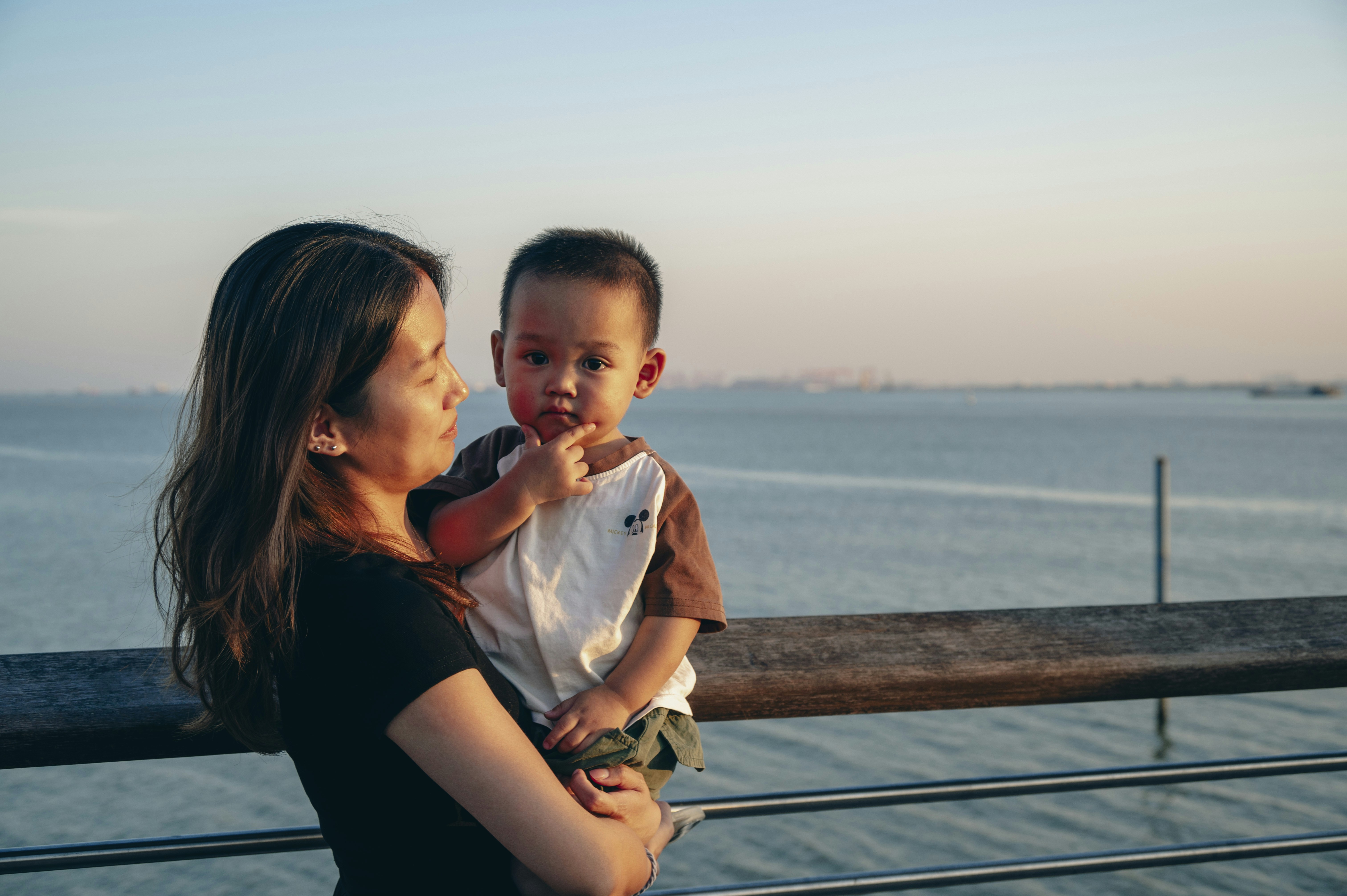 Seorang wanita menggendong seorang anak kecil di dekat badan air