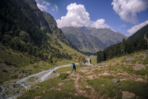 A man standing in a valley with mountains in the background