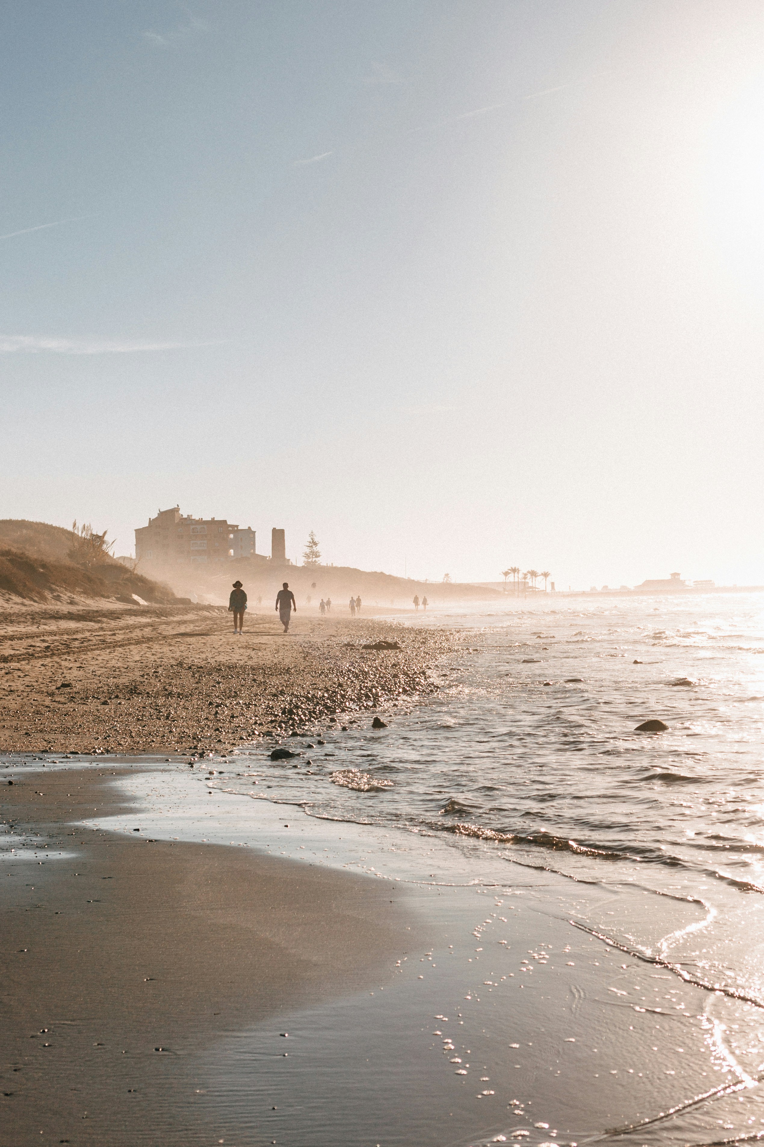 A sandy beach with people walking on it