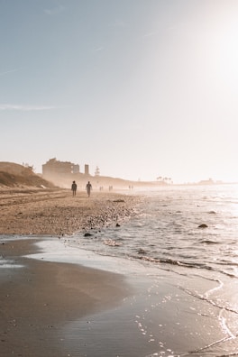 A sandy beach with people walking on it