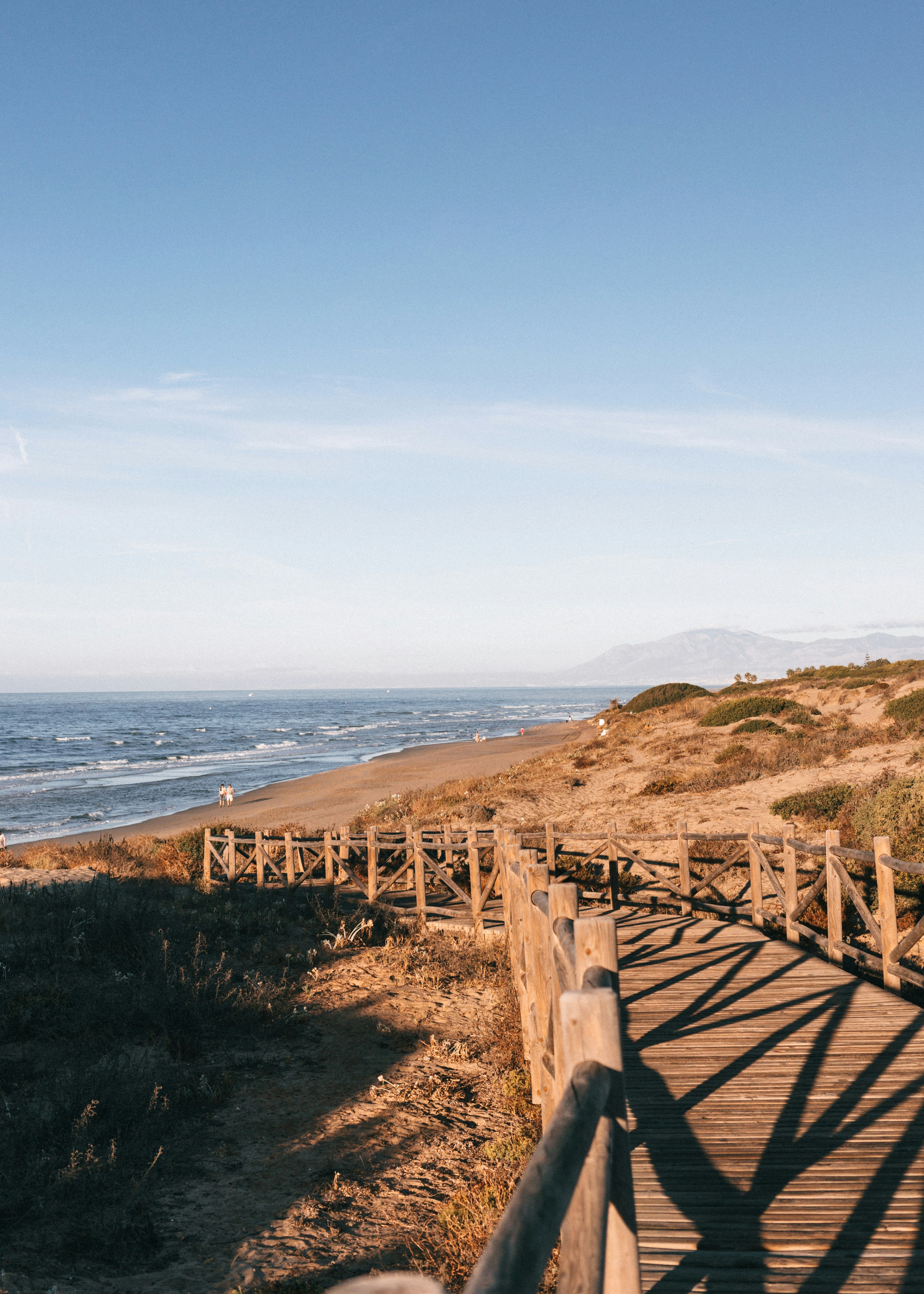 A wooden walkway leading to the beach on a sunny day